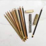 Art supplies set with pencils markers and colored pencils arranged on a white marble surface